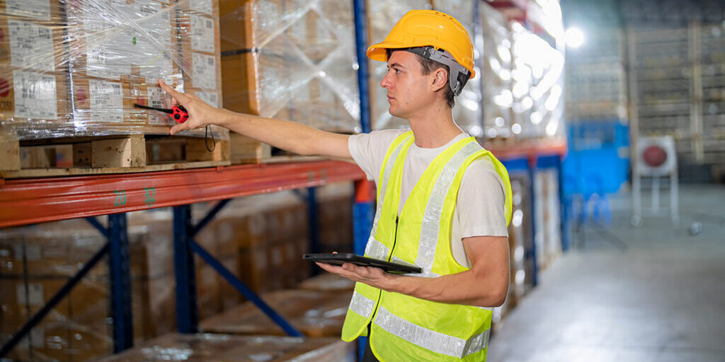 Man working at the warehouse taking inventory Warehouse workers with uniform working in distribution warehouse.